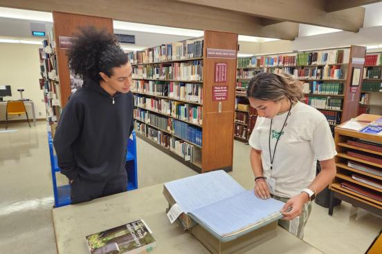 Two students studying an old book in the library