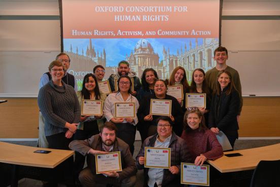 People posing with certificates in front of a slide that reads OCHR: Human Rights, Activism, and Community Action