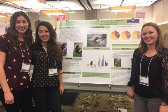 three students standing with their poster at a conference