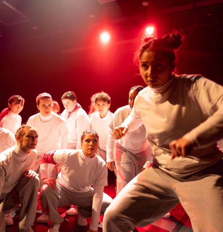 Performers wearing white dancing under red light