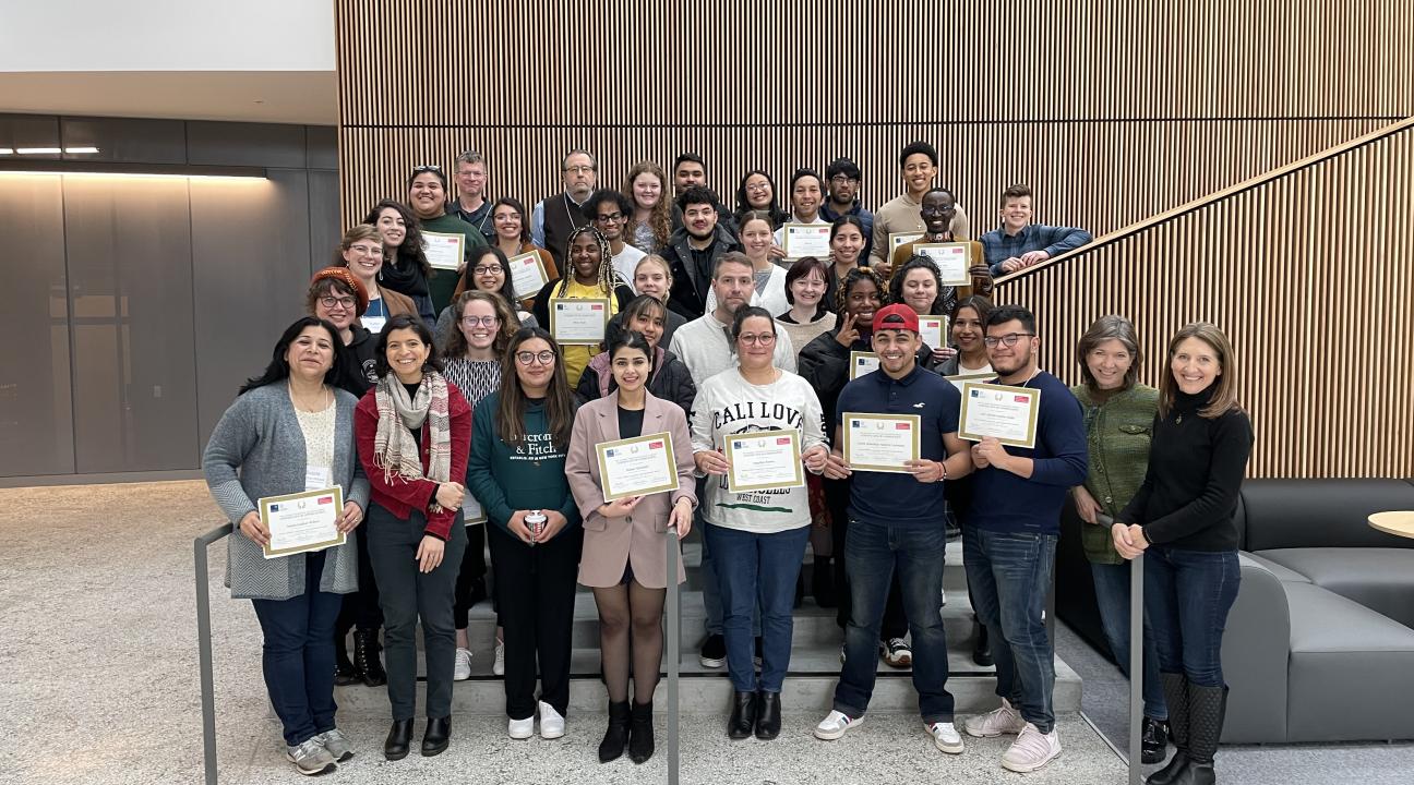 Many smiling people pose on a staircase 