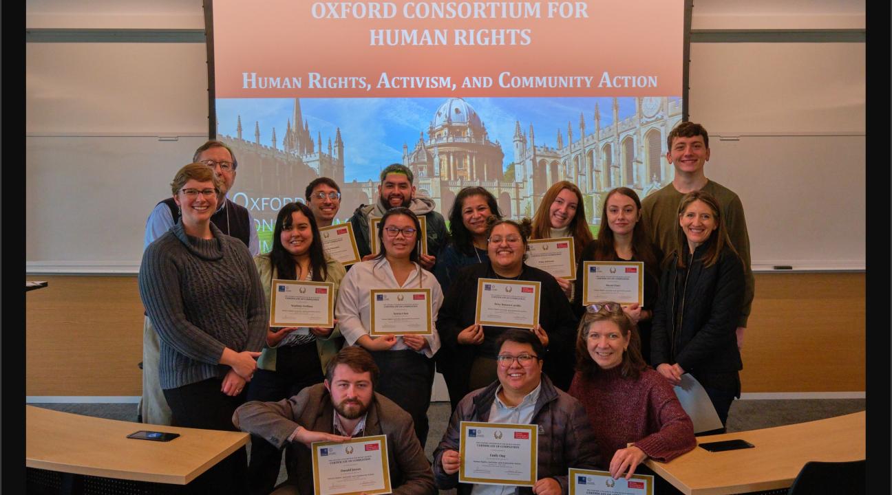 A group of people with certificates in front of a slide that reads Human Rights, Activism, and Community Action