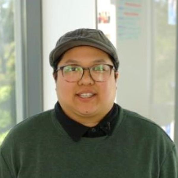 A student standing in a light-filled hallway