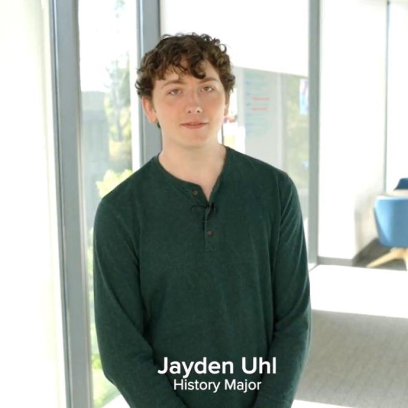 A student standing in a light-filled hallway