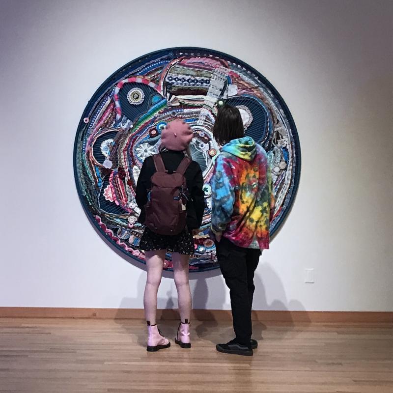 Two people standing in the Art Gallery admiring a piece of art