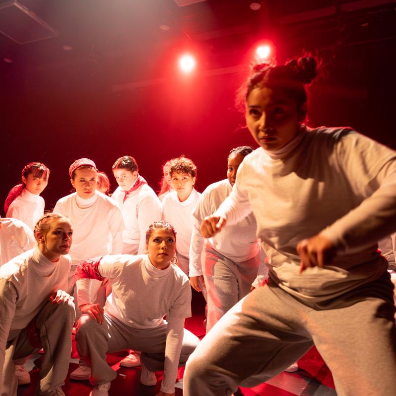 Performers wearing white dancing under red light