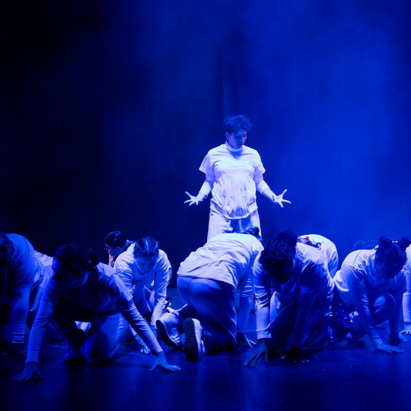 Performers wearing white dancing under blue light