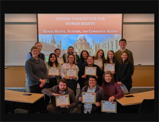 A group of people with certificates in front of a slide that reads Human Rights, Activism, and Community Action